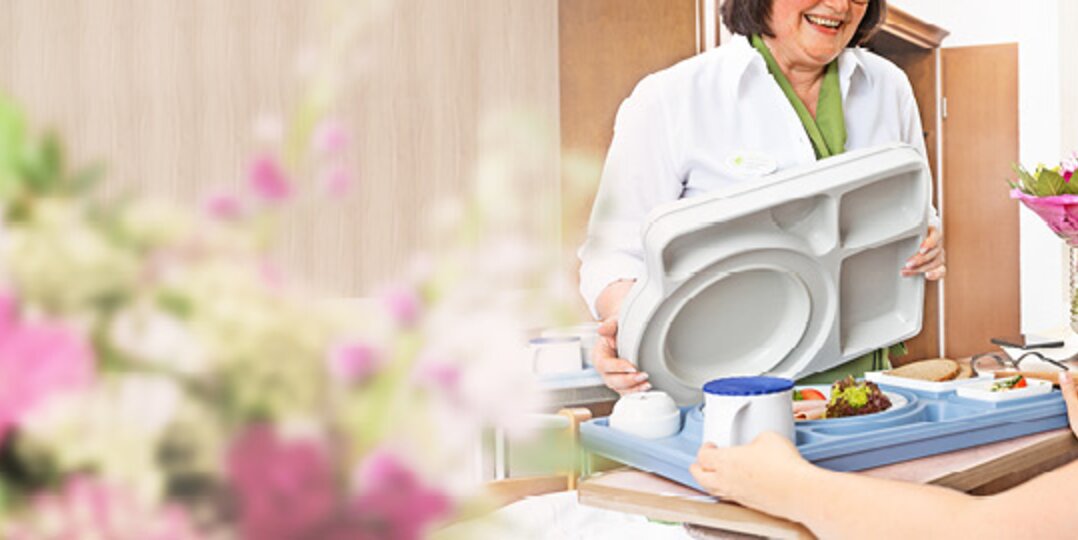 Nurse serves food to patient in bed